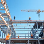 Workers assembling structural steel construction beams at a bright construction site.